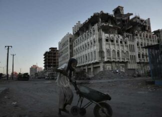 An elderly man walks past a damaged building in Aden, Yemen, in 2018.