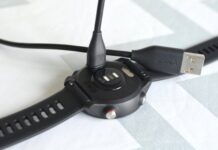 A charging and sync cable is seen going in to the back of a Garmin watch