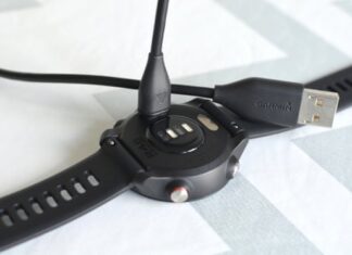 A charging and sync cable is seen going in to the back of a Garmin watch